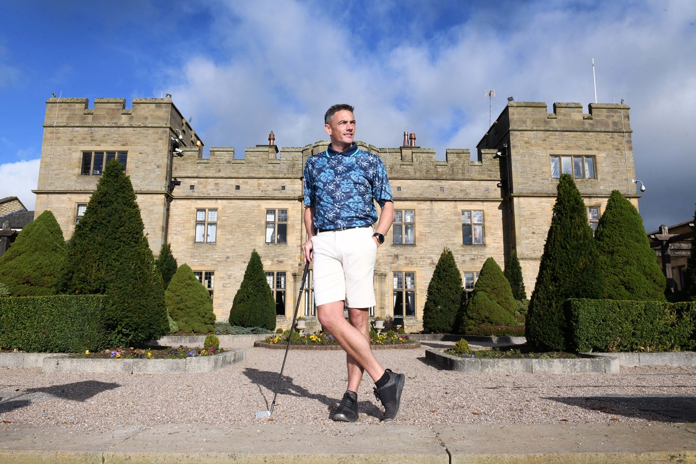 Fashionable golfer stood in front of stately home